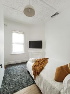 a white bedroom with a bed and a flat screen tv at Stunning Queen Room 1Min Walk to Station with 55 Inch TV in Sydney