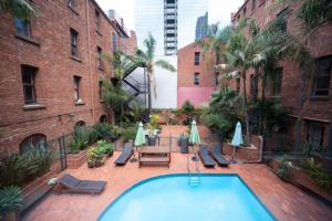 einen Pool im Innenhof mit Stühlen und Sonnenschirmen in der Unterkunft Gordons Place Entire Apartment CBD Location in Melbourne