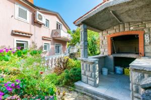 an outdoor pizza oven in a garden next to a house at Apartments Antonija in Kampor
