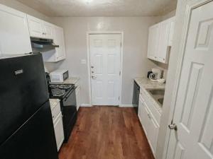 a kitchen with white cabinets and a black refrigerator at Workforce Ready 2 bedroom Home in Corpus Christi