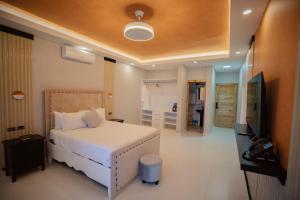 Schlafzimmer mit einem weißen Bett und einem TV in der Unterkunft Brunei Hotel Boutique in Boca Chica