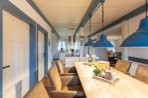 a kitchen and dining room with a wooden table and blue pendants at Juwel am Deich in Emmelsbüll-Horsbüll