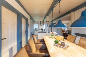 een keuken en eetkamer met een houten tafel en blauwe hangers bij Juwel am Deich in Emmelsbüll-Horsbüll