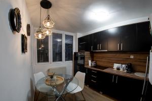 a kitchen with a glass table and black cabinets at The SKVER-Elegant City Apartmant in Požarevac
