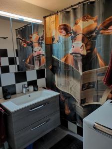 a bathroom with a shower curtain with a picture of a cow at Camenzind in Gersau