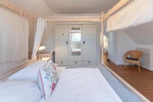 ein Schlafzimmer mit einem großen weißen Bett mit Baldachin in der Unterkunft Juwel am Deich in Emmelsbüll-Horsbüll