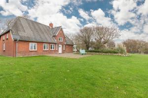 een rood bakstenen huis met een groen gazon bij Juwel am Deich in Emmelsbüll-Horsbüll