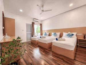 Raalhu Fonu Maldives في Mahibadhoo: غرفة معيشة بها سريرين وأريكة