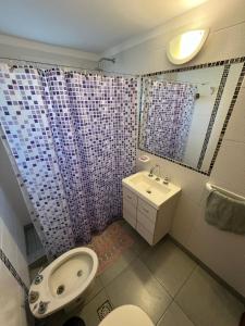 a bathroom with a sink and a toilet and a mirror at Departamento Libra XX Frente al mar! Promos primavera! in Villa Gesell +18 photos