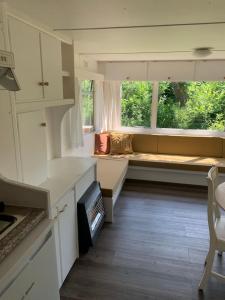 a living room with a couch and a window at Stacaravan met tuin aan de Waddenzee in Oosterend