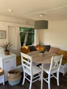 cocina con mesa, sillas y sofá en Stacaravan met tuin aan de Waddenzee, en Oosterend