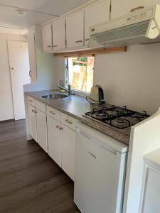 a kitchen with white cabinets and a stove top oven at Stacaravan met tuin aan de Waddenzee in Oosterend