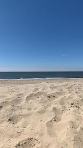 a beach with footprints in the sand and the ocean at Stacaravan met tuin aan de Waddenzee in Oosterend