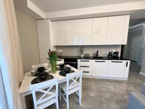 a kitchen with white cabinets and a table and chairs at Apartament nad Łyną by RENT4YOU in Olsztyn