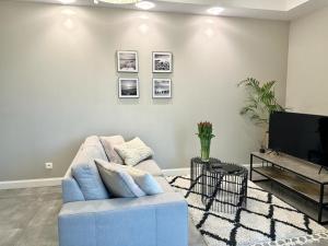 a living room with a blue couch and a tv at Apartament nad Łyną by RENT4YOU in Olsztyn