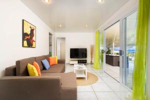 a living room with a couch and a television at Nunaatini Lodge in Faaa