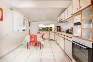 una cocina con armarios blancos y una mesa con sillas rojas en Nunaatini Lodge en Faaa