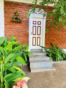 ein Backsteingebäude mit einer weißen Tür und einer Treppe in der Unterkunft Sky 14 Resort Yala in Madam
