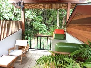 eine abgeschirmte Veranda mit einem Sofa und Stühlen darauf in der Unterkunft The Reef Hotel & Studios in Ko Lipe