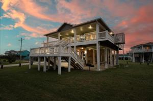 a large house with a staircase in the grass at Hot Tub Golf Cart Near beach Coastal Retreat in Bolivar Peninsula