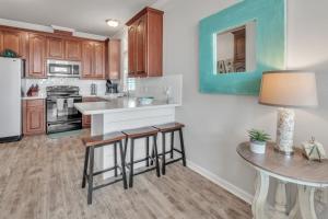 a kitchen with wooden cabinets and a table with stools at Steps to beach Golf Cart About Time Beach Retreat in Bolivar Peninsula