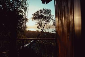 uma vista para o pôr-do-sol a partir de uma varanda com uma árvore em Cabanas Por do Sol em Garopaba