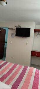 - une chambre avec un lit et une télévision murale dans l'établissement Hotel Alta Vista Campestre, à Tibasosa