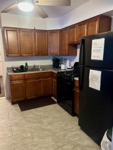 a kitchen with wooden cabinets and a black refrigerator at A Spacious & Blissful Stay in queens in Laurelton