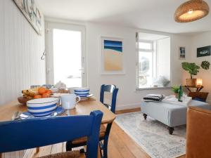 a dining room with a table with blue chairs at Waves End in St Austell