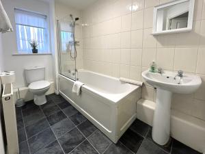 a bathroom with a tub and a sink and a toilet at Hindmarsh Apartment in Ashington