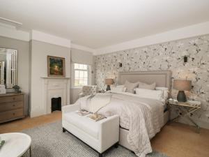 um quarto com uma cama branca e uma cadeira branca em The Gate House em Cirencester