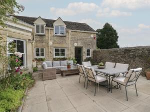 a patio with a table and chairs in front of a house at The Gate House in Cirencester