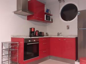 uma cozinha com armários vermelhos e um forno preto em A L'Arche Bleue em Le Robert