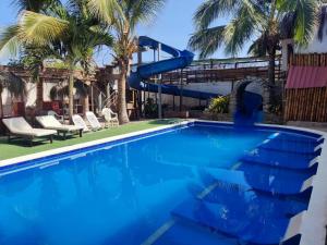 a blue swimming pool with a water slide at MAU Suite&Apartment in Máncora