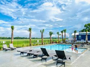 a swimming pool with lounge chairs and palm trees at Vacation Cottage North Myrtle Beach 67 in Myrtle Beach