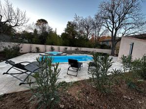 une piscine avec deux chaises et une table dans l'établissement Bastide avec Piscine et Spa, vue Ste Victoire, au Tholonet