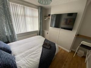 a bedroom with a bed and a flat screen tv at Connswater Town House Belfast in Belfast