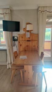 mesa de comedor de madera con TV en la pared en Appartamento Dolomiti 138 Villaggio Turistico en Carbonin