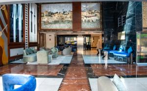 a lobby with blue chairs and paintings on the wall at Social Hotel formerly Byblos in Dubai