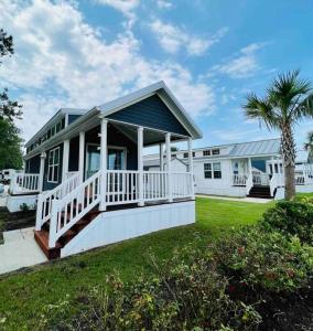 a white house with a porch and a palm tree at Vacation Cottage North Myrtle Beach 65 in Myrtle Beach