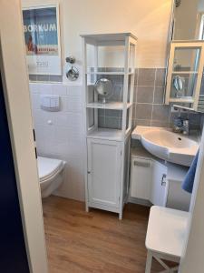 ein kleines Bad mit einem Waschbecken und einem WC in der Unterkunft Ferienwohnung Antje auf Borkum in Borkum