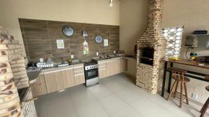 cocina con fogones y chimenea de ladrillo en Central Praias Suíte 2, en Cabo Frío