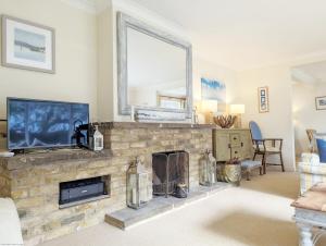 a living room with a stone fireplace and a tv at Fishermans Cottage, Felpham in Felpham