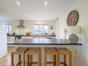 a kitchen with a large counter with stools in it at Fishermans Cottage, Felpham in Felpham