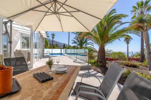 a dining table with an umbrella on a patio with palm trees at Villa MeiNora in El Paso +29 photos