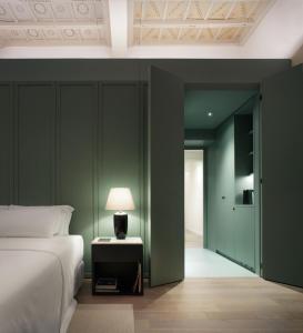 ein Schlafzimmer mit grünen Wänden, einem Bett und einer Lampe in der Unterkunft Parisii Bocca di Leone 88 in Rom
