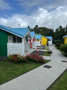 a row of colorful houses with flowers in a yard at Hotel Le Rotabas in Sainte-Anne