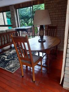 a table with a lamp and a chair on a porch at Whispering Waves in Van Stadensriviermond