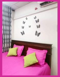 a bed with pink sheets and butterflies on the wall at GREEN GRASS HOUSE in Colombo