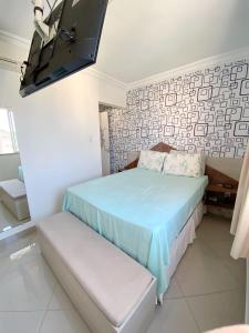 a bedroom with a bed and a tv on the wall at Apartamento confortável Ilhéus in Ilhéus